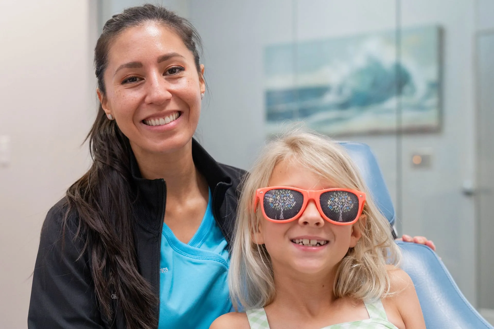 Smiling orthodontist and child wearing sunglasses in dental office, showcasing a friendly environment for kids' orthodontic consultations at St. Johns Orthodontics.